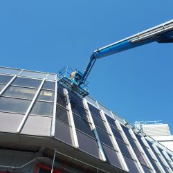 Cherry Picker Raised High Against Windows For Cleaning